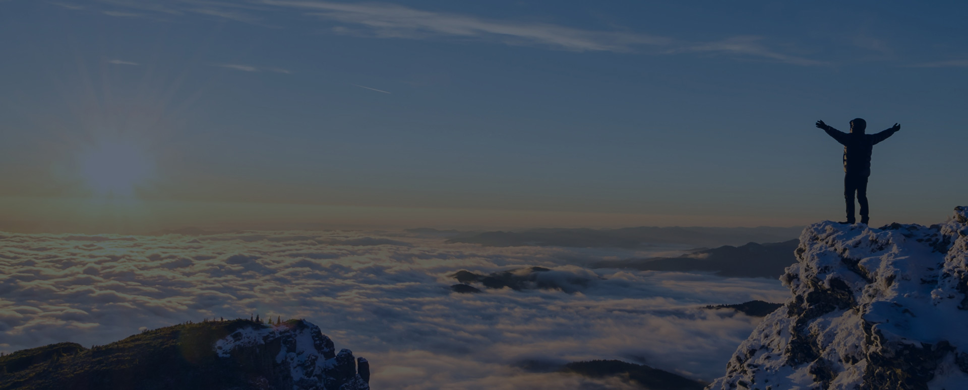 Man standing on snowy mountain top overlooking the clouds