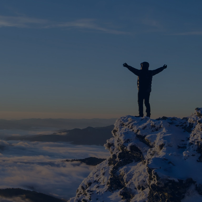 Man standing on snowy mountain top overlooking the clouds