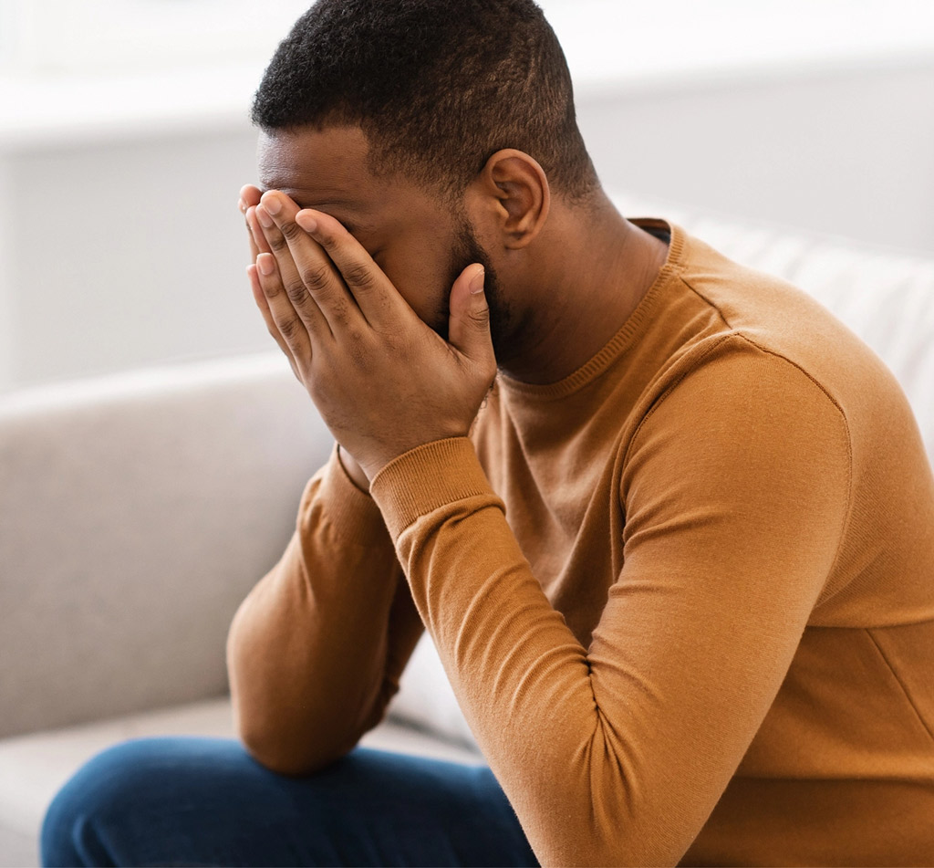 Anxious man holds his head in his hands