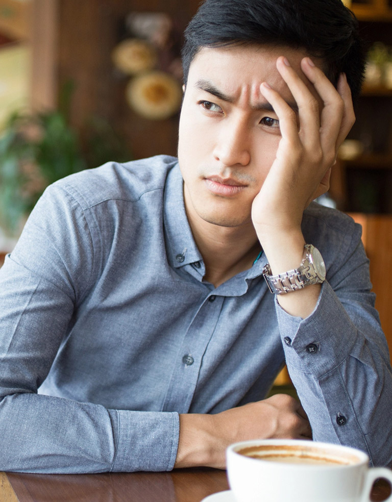 Bored young Asian man sitting in cafe