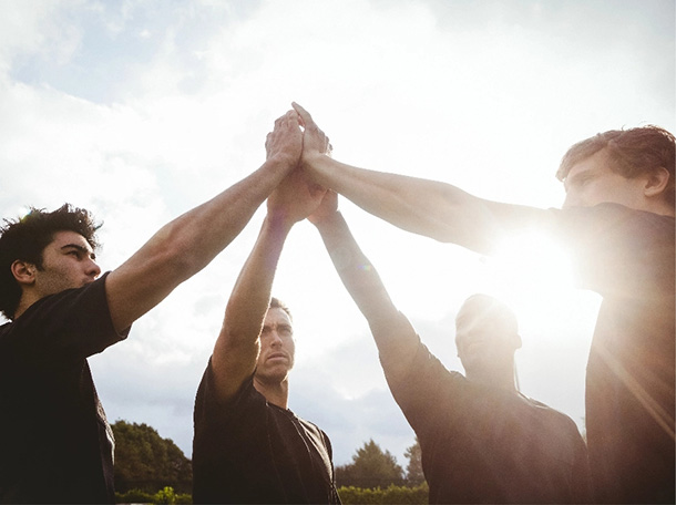 Four friends hands up with sunburst