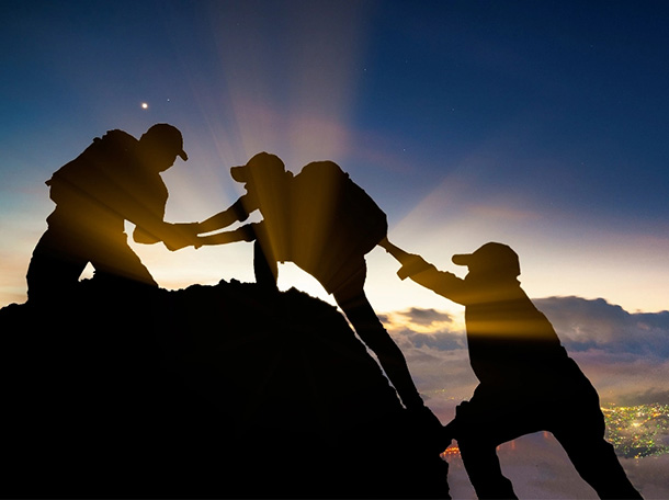 Friends helping each other climb mountain 1