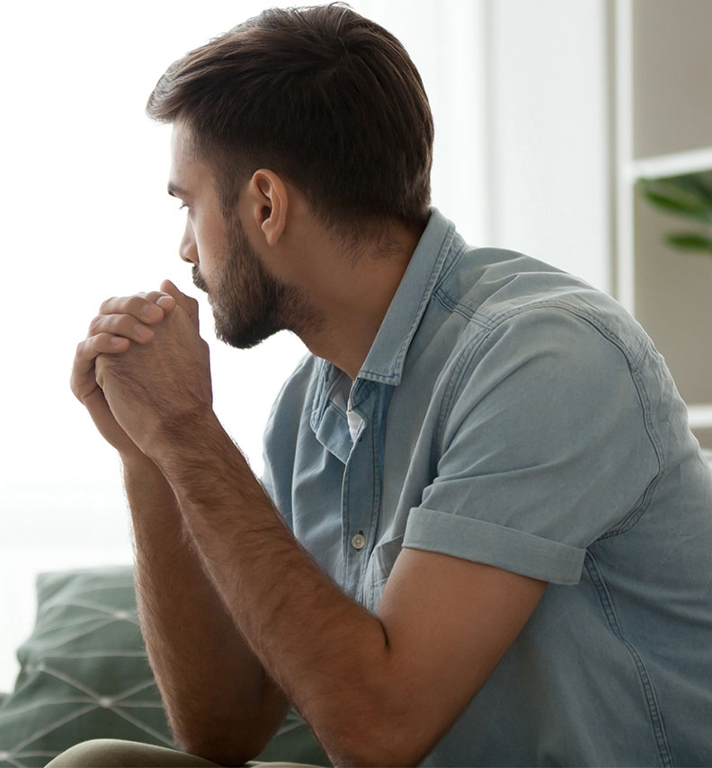 Man with hands clasped looking away