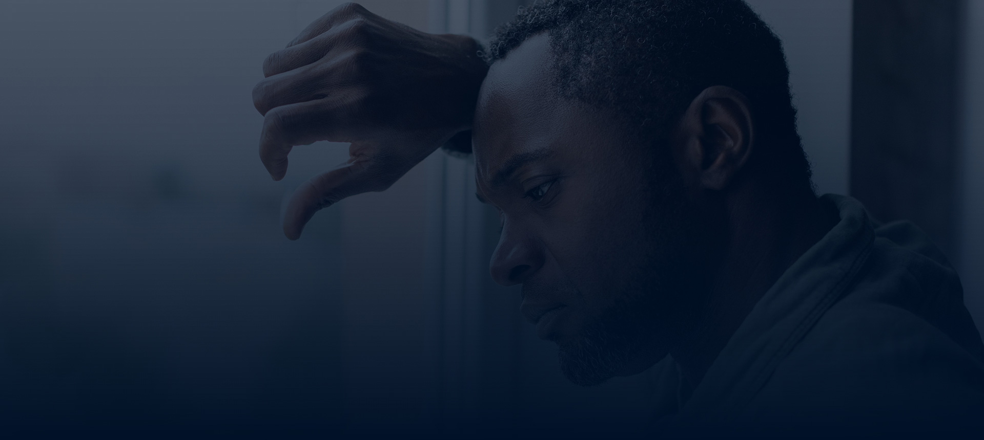 Sad depressed man leaning against rainy window